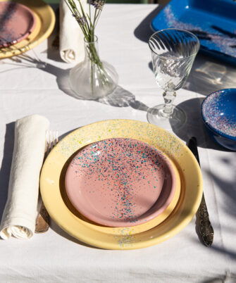 Petite assiette en acier émaillé artisanale LORI coloris rose sur table dressée avec assiette plate jaune — Maison Levantine