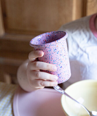 Petit gobelet en acier émaillé artisanale LORI coloris rose dans main d'enfant — Maison Levantine
